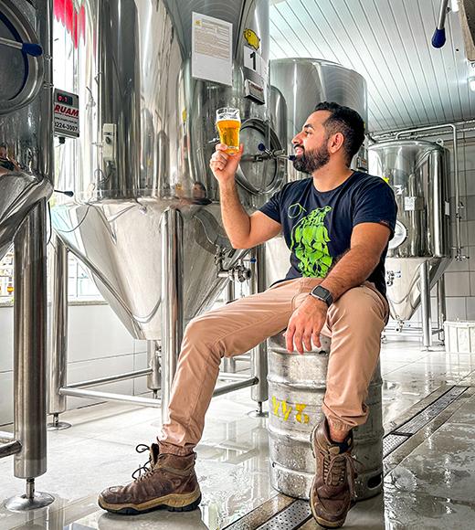 Brewer Matheus Ramos poses with beer in a brewery