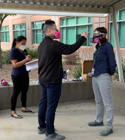 Leong and colleague conduct fit testing of a respirator