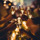 multiple people hold of champagne glasses in a celebratory toast
